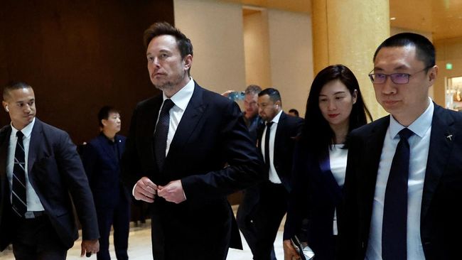 Chief Executive Officer Tesla Elon Musk berjalan di samping Wakil Presiden Senior Tesla Tom Zhu dan Wakil Presiden Grace Tao saat dia meninggalkan sebuah hotel di Beijing