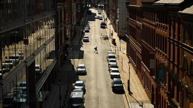 Seorang pejalan kaki melintasi jalan kosong di Birmingham